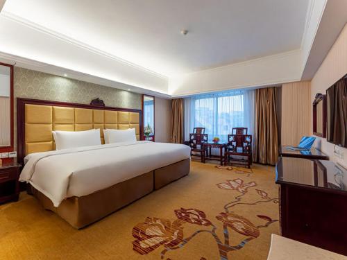 a large bedroom with a large bed and a desk at Vienna Hotel Jingxi Zhongshan Park in Jingxi