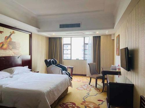 a hotel room with a bed and a desk and chairs at Vienna Hotel Foshan Nanhai City Square in Foshan