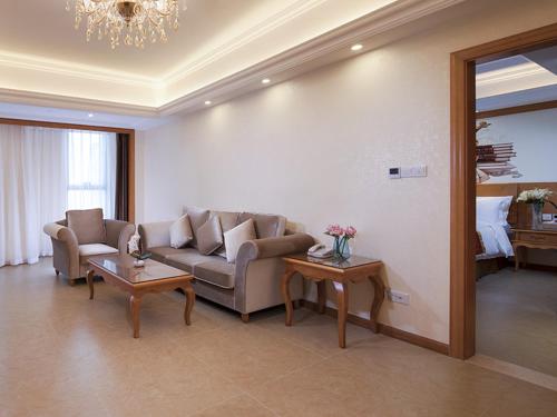 a living room with a couch and two tables at Vienna International Hotel Guangdong Yangjiang Zapo Travel Avenue in Lizao