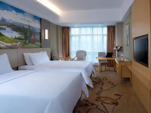 a hotel room with two beds and a flat screen tv at Vienna Hotel(HaiKou High Speed Railway East Station) in Haikou