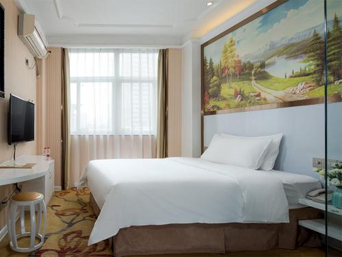 een slaapkamer met een wit bed en een schilderij aan de muur bij Vienna 3 Best Hotel Guangxi Nanning Station in Nanning