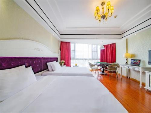 Una gran habitación de hotel con dos camas y una mesa. en Vienna Hotel Guilin Exposition Center, en Guilin