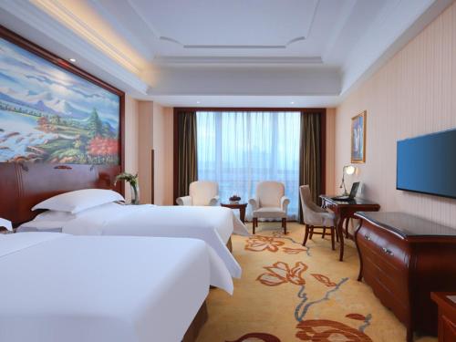 a hotel room with two beds and a flat screen tv at Vienna International Hotel Nanchang Xinjian Center in Nanchang