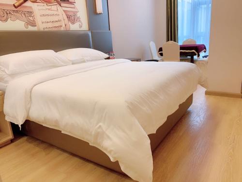 a bedroom with a large bed with white sheets at Vienna Hotel (Shanghai jinshanwei Railway Station City Beach Shop) in Jinshan