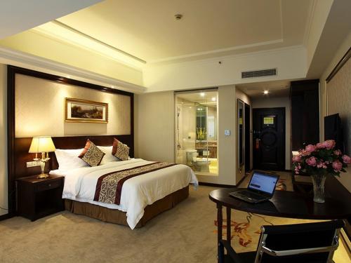 a bedroom with a bed and a desk with a laptop at Vienna International Hotel Changzhou Railway Station in Changzhou