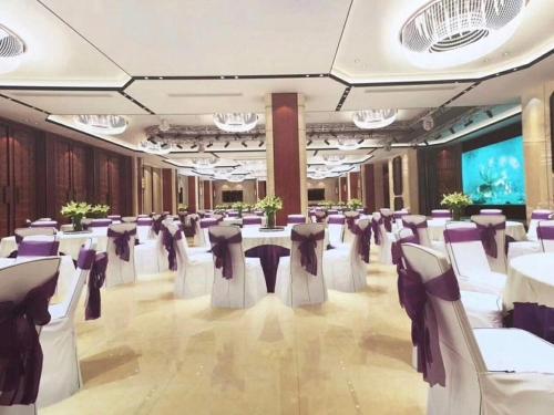 a banquet hall with white tables and purple chairs at Vienna International Hotel Jieyang People's Avenue in Jieyang