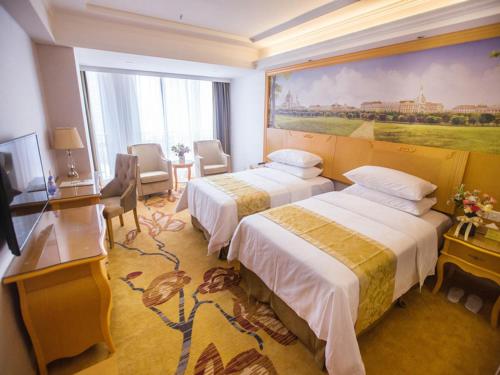 a hotel room with two beds and a painting on the wall at Vienna Hotel Guangdong Huizhou Jiangbei Sanxin in Huizhou