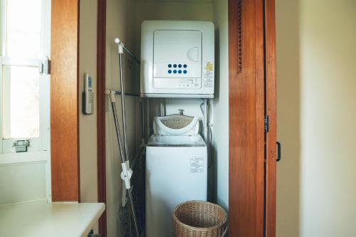 eine kleine Küche mit Mikrowelle und Kühlschrank in der Unterkunft ゲストハウスジャパン西伊豆/The Guest House Japan Nishi-Izu in Toda