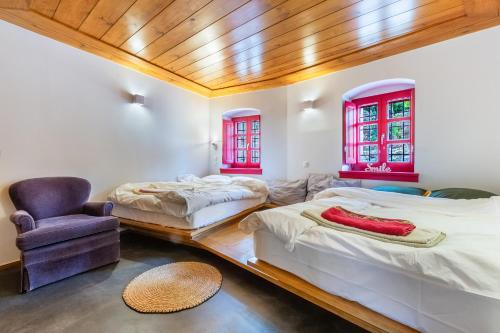 2 camas en una habitación con ventanas rojas y silla en The Land Beyond en Vitsa