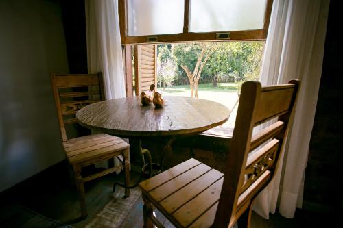a table and chairs in a room with a window at Pouso do Bichinho 1 in Bichinho