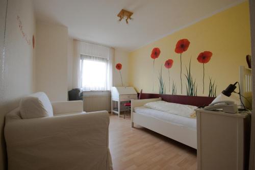 un soggiorno con divano e fiori rossi sul muro di Hotel Scharfes Eck a Mühlacker