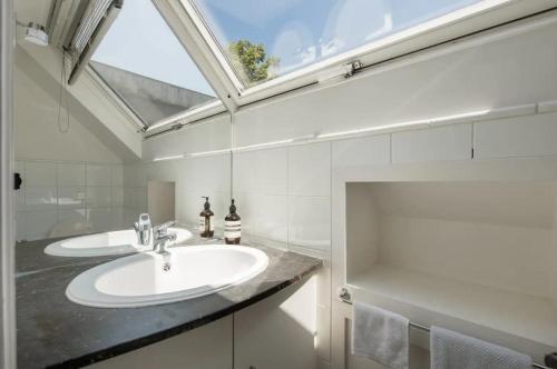 een badkamer met een wastafel en een dakraam bij The Pink House in Brussel