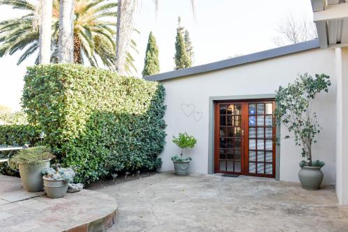 a white building with a red door and plants at Bella's B&B in Vryheid