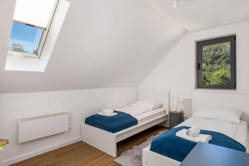 two beds in a white room with a window at Modern Alpine Monsalbius Chalet in Baške Oštarije