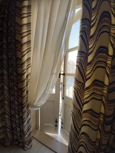 a window with curtains in front of a door at Ayla Studio House in Birżebbuġa