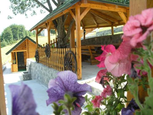 a wooden gazebo with purple flowers in front of it at Motel Krstac in Mojkovac