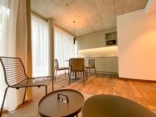 a living room with chairs and a table and a kitchen at Blackhome Innsbruck City South I contactless check-in in Innsbruck