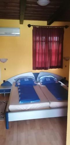 a large bed in a room with a red window at Toscana Panzió in Zalacsány