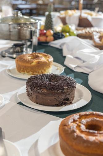 a table with three different types of donuts on plates at Vila Dom Bosco in Campos do Jordão