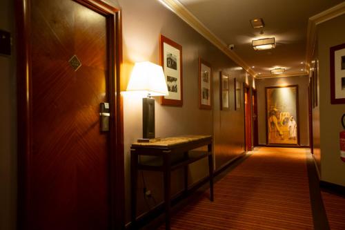 a hallway with a table with a lamp on it at Hotel Atlantic Agdal in Rabat