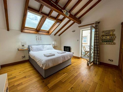 a bedroom with a large bed with wooden floors and windows at Harbourside Apartments in Portpatrick