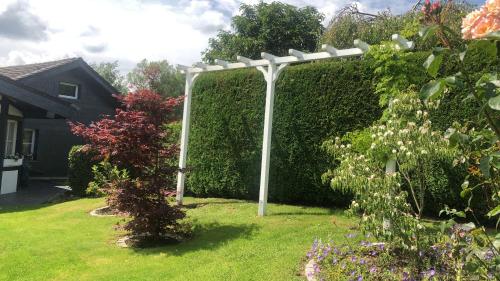 a white pergola in a garden with a hedge at Wohnen im bergischen Fachwerk in Overath