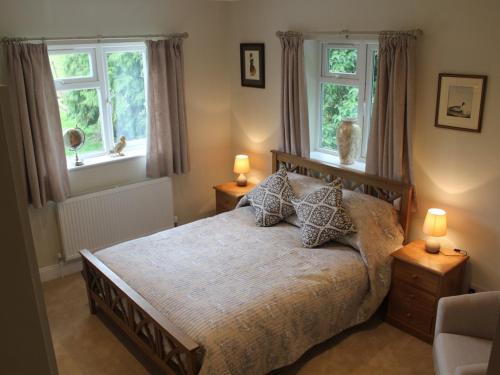 a bedroom with a large bed with two windows at Sunny Nest in Bourton on the Water