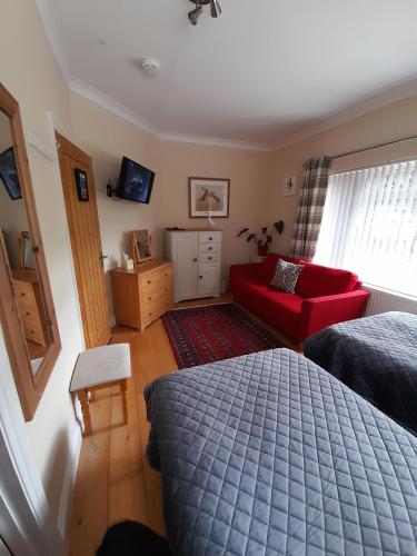 a bedroom with a red bed and a red couch at Sunny Nest in Bourton on the Water