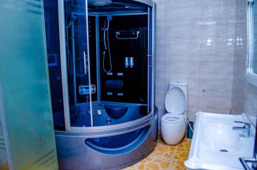 y baño con ducha, aseo y lavamanos. en CRISPAN SUITES & EVENT CENTRE, en Jos