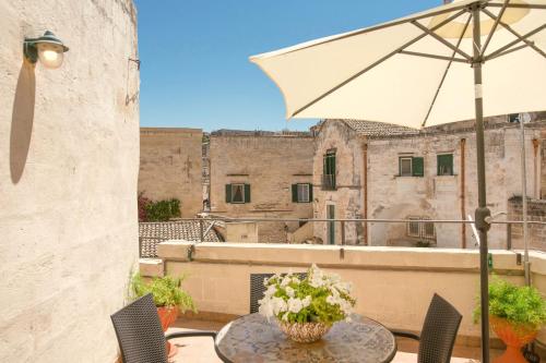 a patio with a table and an umbrella on a balcony at La Casa di Ele in Matera