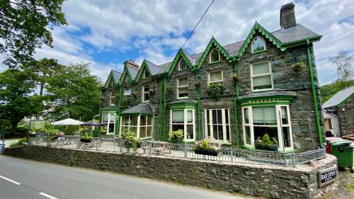 a green stone house with a fence on the side of the street at Hafan Artro in Llanbedr