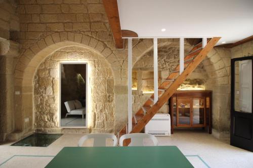 a room with a stone wall with a staircase and a table and chairs at HISTORIA- Dimore Vico Ghezzi in Carpignano Salentino