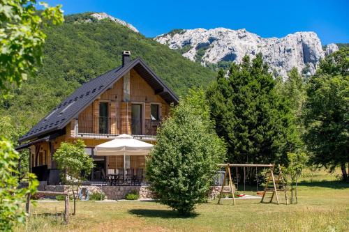 ein Haus mit einem Spielplatz vor einem Berg in der Unterkunft Modern Alpine Monsalbius Chalet in Baške Oštarije