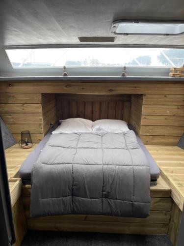 Bett in der Mitte eines kleinen Zimmers mit Fenster in der Unterkunft Exceptionnel bateau maison reine mathilde in Ouistreham