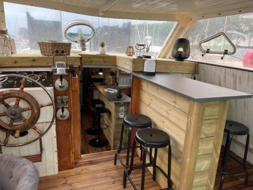 une cuisine avec un comptoir et des tabourets dans un bateau dans l'établissement Exceptionnel bateau maison reine mathilde, à Ouistreham