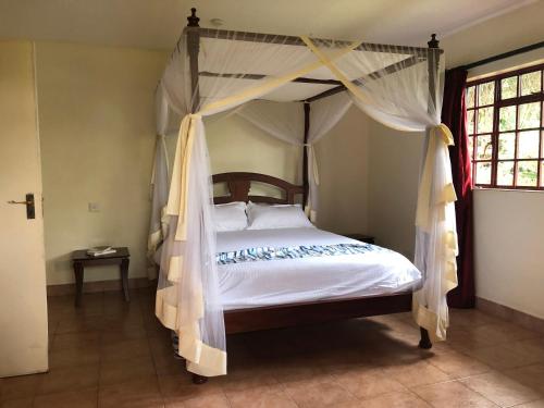 ein Schlafzimmer mit einem Himmelbett in der Unterkunft Twiga Hill Gardens in Nairobi