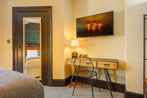a bedroom with a desk with a television on the wall at Brewhouse and Kitchen in Worthing