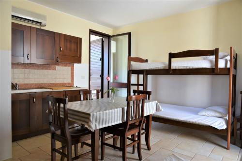 a kitchen and dining room with a table and bunk beds at Residence Club Costa D'Oriente in Torre dell'Orso