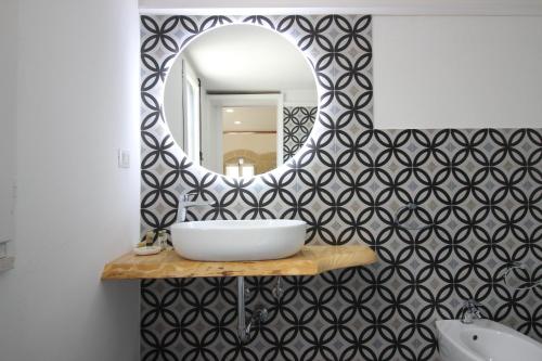 a bathroom with a sink and a mirror on a wall at HISTORIA- Dimore Vico Ghezzi in Carpignano Salentino