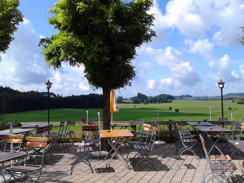 a patio with tables and chairs and a tree at Gasthof Grüner Baum "Kongo" in Amtzell