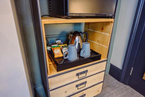 a cabinet with two mugs and a tea pot in it at Brewhouse and Kitchen in Worthing