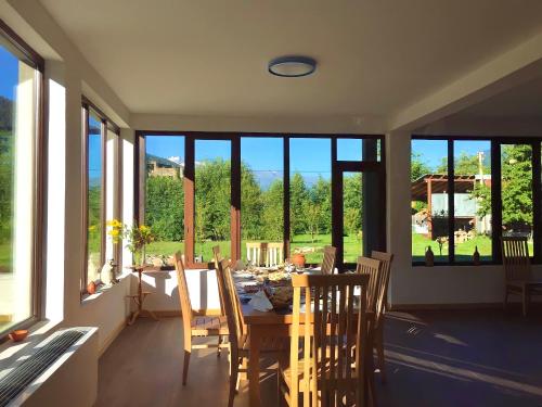 a dining room with a table and chairs and windows at Beko’s garden Inn in Mestia