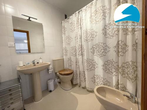 a bathroom with a sink and a toilet and a shower curtain at La Puntica Carboplaya in Carboneras
