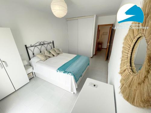 a white bedroom with a bed and a mirror at La Puntica Carboplaya in Carboneras