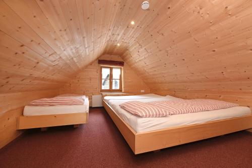 two beds in a room with a wooden ceiling at Der BiscHOF in Mellau