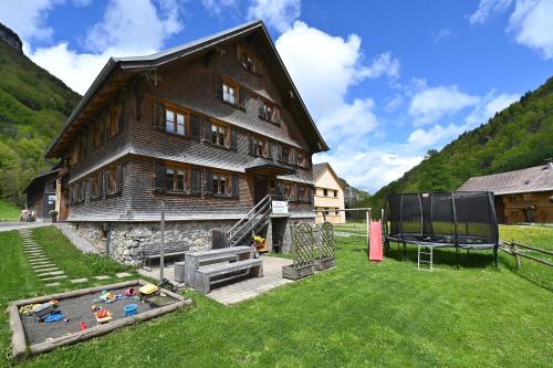 a large wooden house with a playground in the yard at Der BiscHOF in Mellau