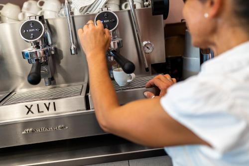 a woman is making a cup of coffee in a espresso machine at Romagna Suite Hotel in Gatteo a Mare