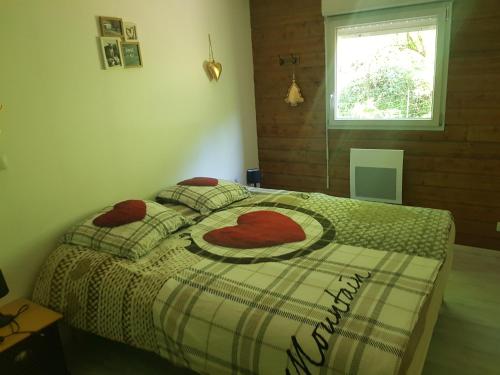 Un dormitorio con una cama con almohadas rojas y una ventana en Appartement cosy calme à l'orée du bois, en Cornimont