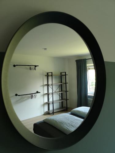 a mirror reflecting a bedroom with a bed and shelves at Haus zur lachenden Lieselotte I 5 Minuten zu Fuß zum kostenlosen Naturbad I Messenähe I Waldnähe in Postbauer-Heng
