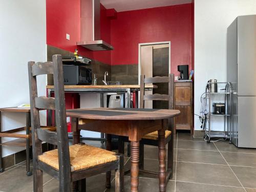 - une cuisine avec des murs rouges, une table et des chaises en bois dans l'établissement VALS-LES-BAINS Source Sirène, à Vals-les-Bains